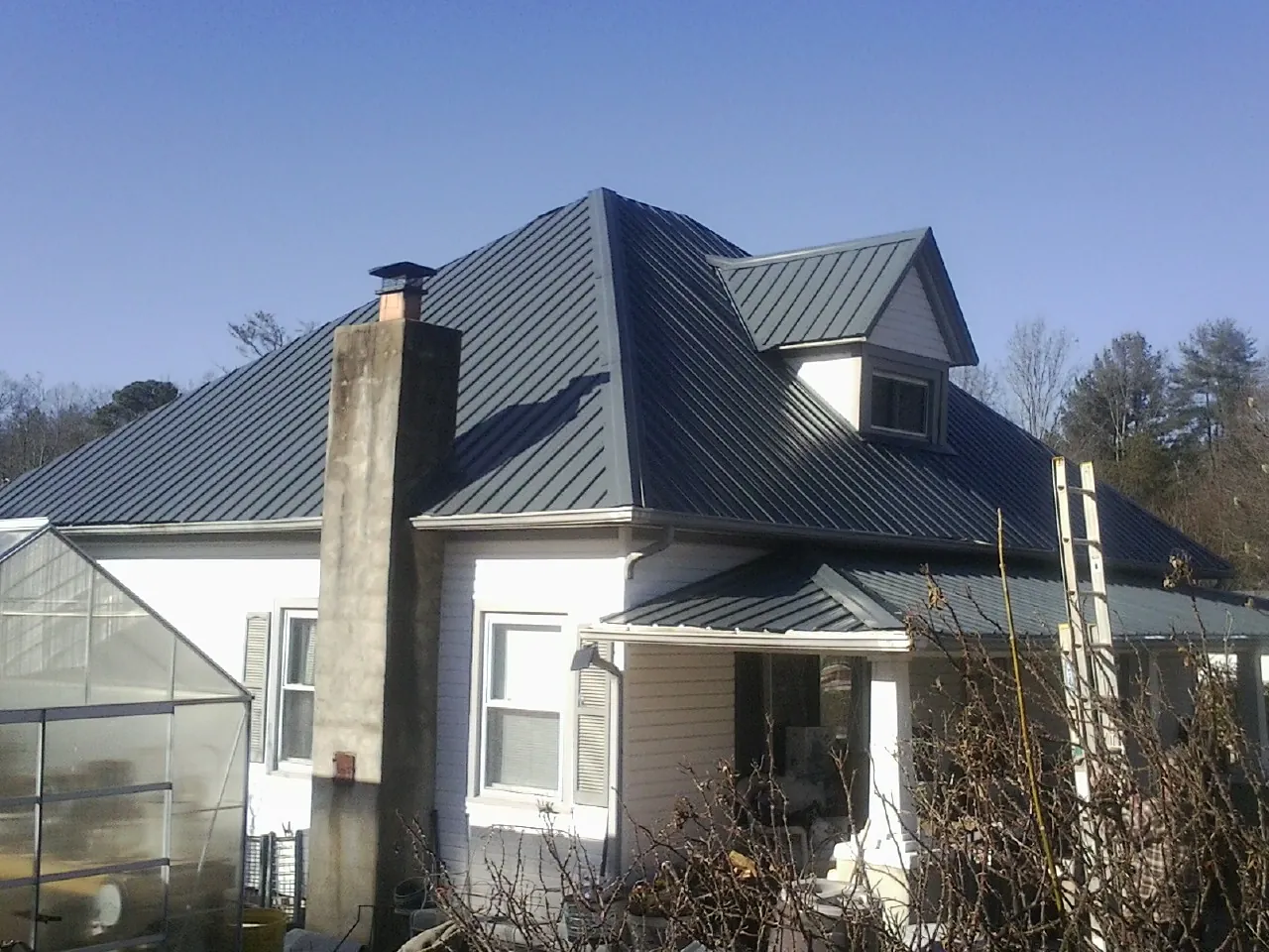 Dark blue standing seam metal roof on a white farmhouse with dormer — Slate & Tile Roof Repair by Roofing Brothers in Fort Loramie