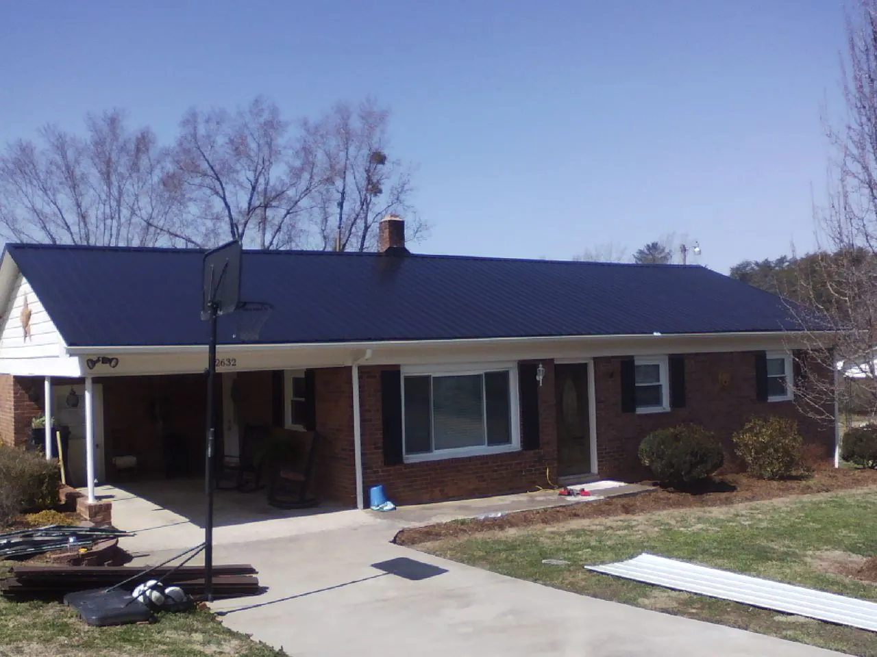 Finished dark blue metal roof on a brick ranch with a carport in Fort Loramie