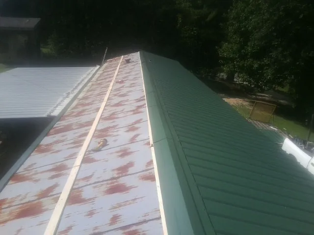 Old rusted panels beside newly installed green metal roofing — Wind Damage Roof Repair by Roofing Brothers in Fort Loramie