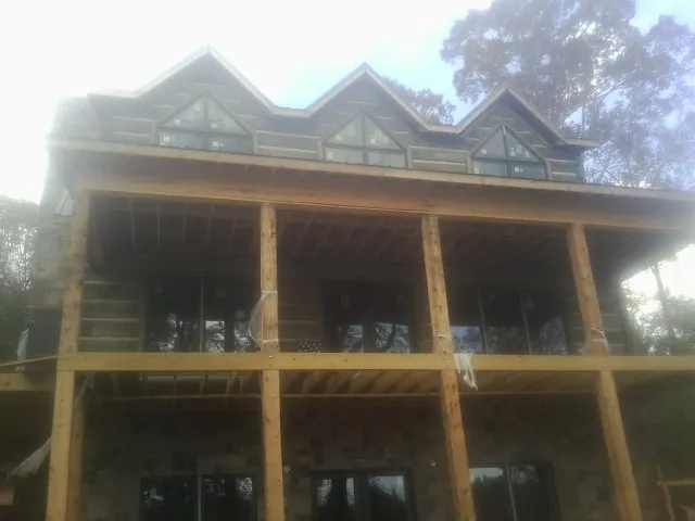 Dormers and porch framing on a large log home under construction — Roof Coating work by our crew in Fort Loramie