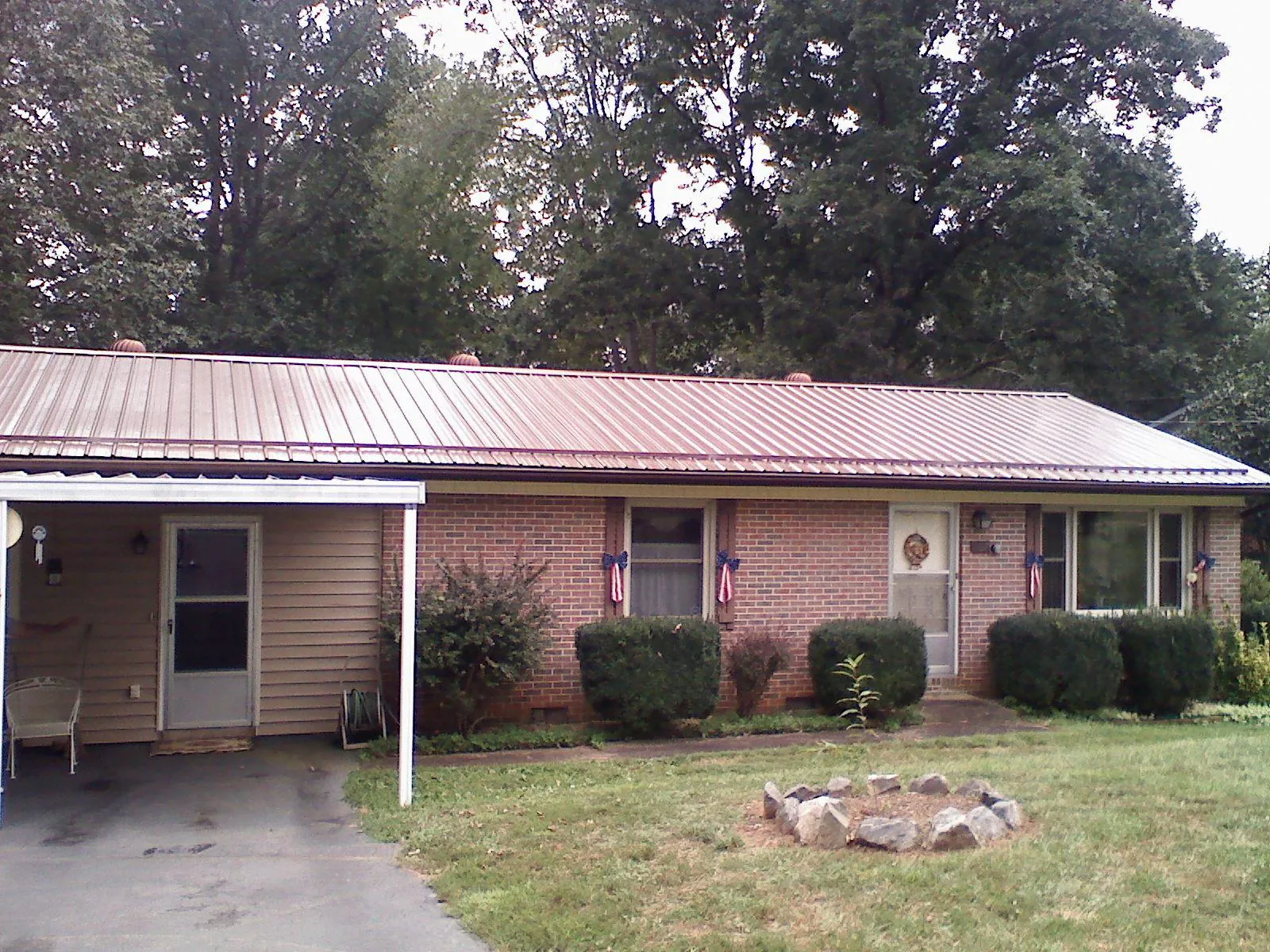Bronze metal roof and carport on a brick ranch home — Roof Repair work by our crew in Fort Loramie
