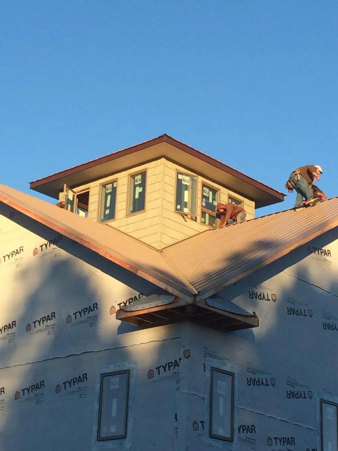 Roofers working around a rooftop cupola on a new metal roof at sunset — Roof Waterproofing in Fort Loramie by Roofing Brothers